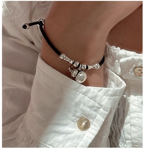 Détail du bracelet en cordon tressé noir avec breloque chat et perle gravée Fu