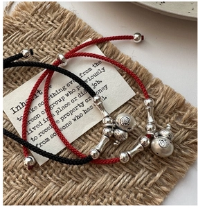 Détail de bracelets tressés rouges et noirs avec breloque Fu en argent S925 poli