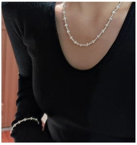 Close-up of minimalist S925 sterling silver beaded necklace and bracelet set on a model