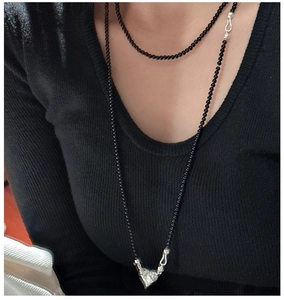 Detail of S925 silver clasp on a minimalist long black onyx bead necklace for layered styling