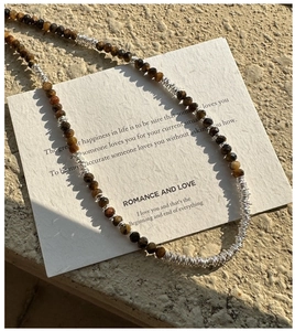 Close-up of brown tiger eye beads and silver wire loops on a 925 sterling silver chain