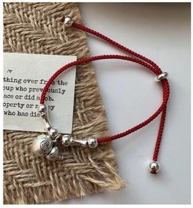 Vue détaillée d'un bracelet en cordon rouge avec pendentif Fu en argent S925 et cloche