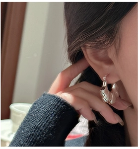 Close-up of wavy S925 silver hoop earrings with a textured croissant-style design