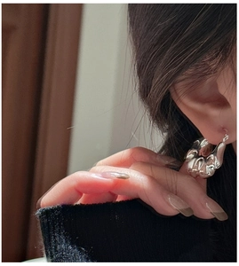 Close-up of a large irregular S925 sterling silver hoop earring with liquid metal texture