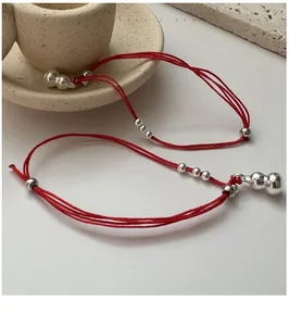 Detailed view of handmade red string bracelets with silver calabash and round beads