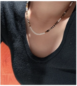 Detail of 925 silver necklace featuring brown tiger eye beads on black knitwear
