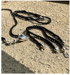 Close-up of black onyx beads and irregular silver heart pendant on a stone surface