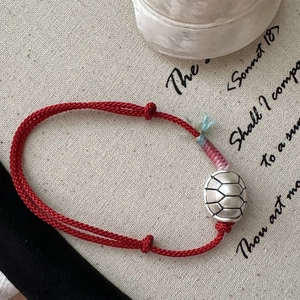 Red braided S925 sterling silver tortoise shell bracelet on vintage canvas background