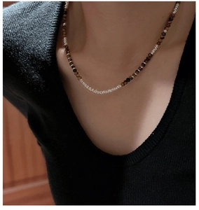 Detail of 925 silver beaded necklace with brown tiger eye stones on model neck
