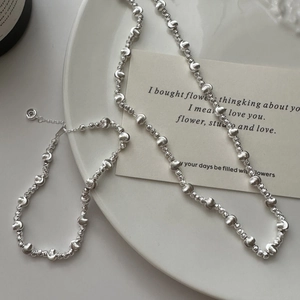 Elegant S925 sterling silver beaded necklace and bracelet set on a white ceramic tray