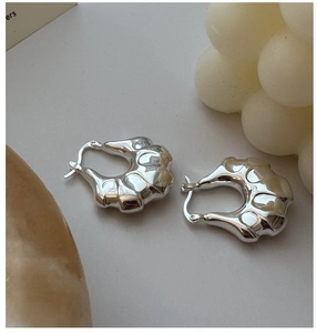 Macro shot of S925 sterling silver hoop earrings with a chunky irregular wave design