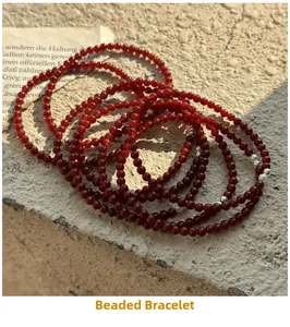 Macro detail of red agate beaded bracelet with pearls on stone texture and vintage paper