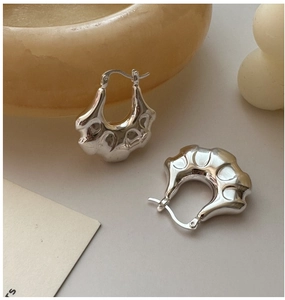 Detail of S925 sterling silver hoop earrings with a modern wavy lava texture and mirror finish