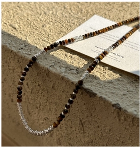 Close-up of brown tiger eye beads and silver wire accents on a layered necklace