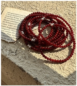 Macro detail of red agate beaded bracelet with silver accents and white pearls on stone
