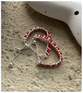 Detailed shot of braided red string bracelet with polished silver beads and charm