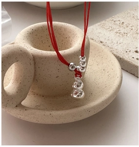 Close-up of minimalist red cord bracelet with silver beads and polished hulu gourd pendant