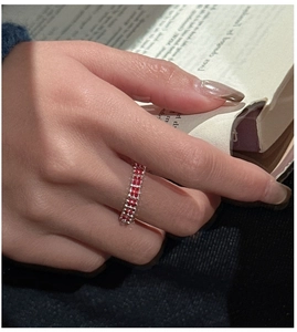 Detail of red cubic zirconia woven ring worn by a model reading an English book