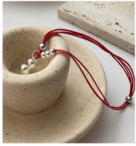 Close-up of minimalist red braided rope bracelet with 925 sterling silver beads decoration