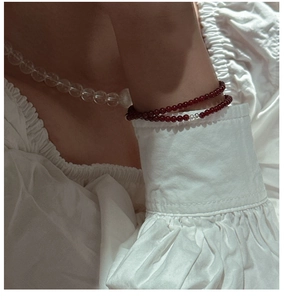 Close-up of red agate beaded bracelet and white necklace on model with linen fabric