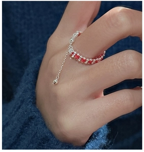 Detail of red braided string ring with S925 silver beads and tassel on blue sweater
