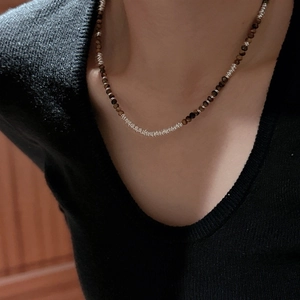 Vintage 925 silver tiger eye beaded necklace worn on a black V-neck collarbone