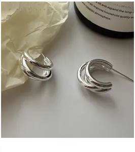 Macro detail of triple-layered S925 sterling silver hoop earrings with polished finish