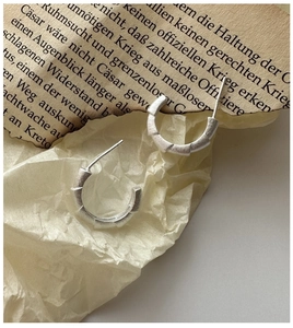 Macro view of C-shaped S925 sterling silver earrings with textured matte finish