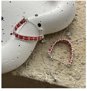 Close-up of red woven bracelets with silver beads and adjustable chain details