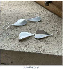 Macro detail of S925 sterling silver frosted heart earrings on a stone surface