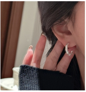 Detail of silver bamboo textured hoop earring worn on ear with minimalist style