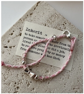 Vue macro du bracelet tissé rose et blanc avec pendentif nœud en argent S925 poli