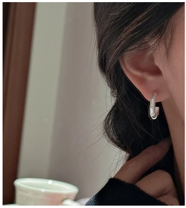 Macro detail of silver C-shape bamboo texture earrings on model with minimalist design