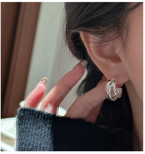 Close-up of S925 sterling silver triple-layer hoop earrings worn by a model