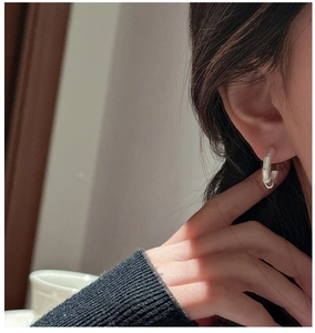 Close-up of minimalist S925 sterling silver bamboo texture earrings on a model