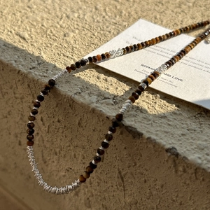 925 silver tiger eye beaded necklace with metallic coils on a minimalist stone display