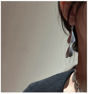 Close-up of model wearing matte S925 sterling silver layered petal drop earrings and necklace