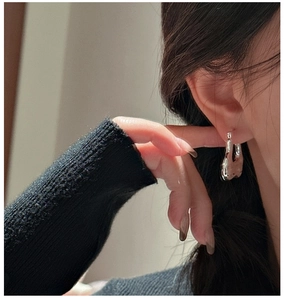 Macro shot of silver U-shaped earrings with liquid metal lava texture on a model