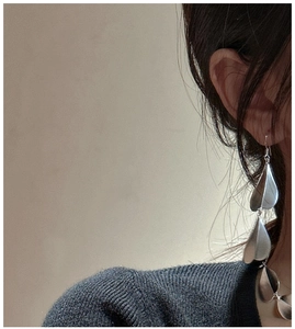Close-up of matte silver S925 tiered leaf drop earrings worn by a model