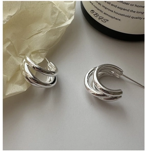 Detail shot of silver S925 triple-layer C-shaped hoop earrings on a textured surface