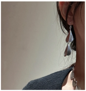 Macro detail of silver frosted teardrop earrings showing elegant matte metal texture