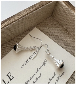 Macro shot of S925 sterling silver retro earrings with black onyx on linen texture