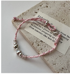 Détail du bracelet en corde tressée rose et blanc avec nœud argenté et fermoir