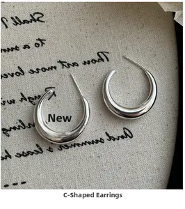 Détail des boucles d'oreilles en C en argent sterling S925 poli sur tissu texturé