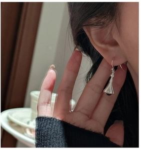 Detail of silver bell-shaped drop earrings with dark beads on female model