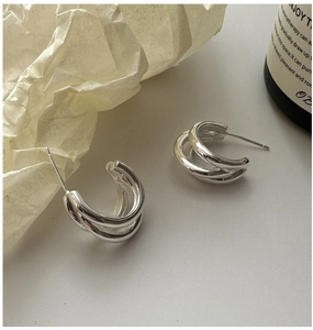 Detailed view of S925 sterling silver triple layer hoop earrings on a textured background