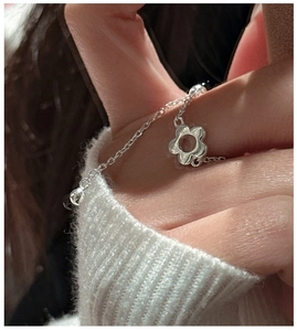Détail d'une bague chaîne fleur évidée en argent sterling S925 sur un doigt
