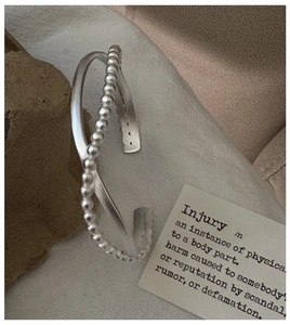 Macro shot of S925 sterling silver matte crossed cuff bracelet on textured fabric