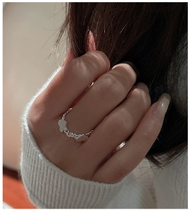 Gros plan d'une bague chaîne en argent S925 avec deux breloques en forme de cœur
