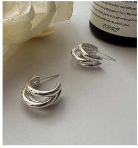 Detail view of triple-layered silver hoop earrings in a stylish C-shaped minimalist design